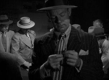 Movie still from “T-Men” (1947), directed by Anthony Mann – A black and white photo of a man tying a tie; Medium shot, Over the shoulder angle