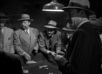 Movie still from “T-Men” (1947), directed by Anthony Mann – A black and white photo of men in suits and hats playing cards; Medium shot, High angle