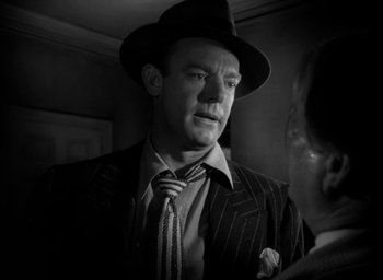 Movie still from “T-Men” (1947), directed by Anthony Mann – A black and white photo of a man in a suit and tie; Close Up shot, Over the shoulder angle