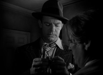 Movie still from “T-Men” (1947), directed by Anthony Mann – A man in a suit and a hat looking down at a woman; Close Up shot, Low angle