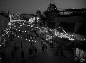 Movie still from “T-Men” (1947), directed by Anthony Mann – A black and white photo of people walking on a boardwalk; Extreme Wide shot, High angle