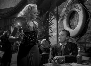 Movie still from “T-Men” (1947), directed by Anthony Mann – A man and a woman are sitting at a table together; Medium shot, Low angle