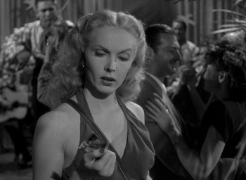 Movie still from “T-Men” (1947), directed by Anthony Mann – An old photo of a beautiful woman in a crowd; Close Up shot, Low angle