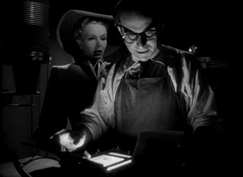 Movie still from “T-Men” (1947), directed by Anthony Mann – A man and a woman are looking at a tablet computer; Medium shot, Low angle