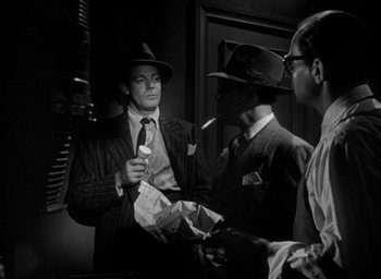 Movie still from “T-Men” (1947), directed by Anthony Mann – A group of men standing next to each other in a room; Medium shot, Over the shoulder angle