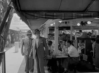 Movie still from “T-Men” (1947), directed by Anthony Mann – A group of people sitting at a table with drinks on it; Wide shot, Low angle