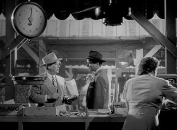 Movie still from “T-Men” (1947), directed by Anthony Mann – Two men and a woman standing in front of a clock; Wide shot, Over the shoulder angle