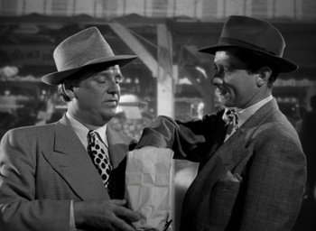 Movie still from “T-Men” (1947), directed by Anthony Mann – Two men in suits and hats holding a paper bag; Medium shot, Over the shoulder angle