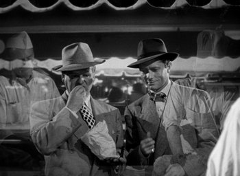 Movie still from “T-Men” (1947), directed by Anthony Mann – A couple of men standing next to each other wearing hats; Medium shot, Low angle
