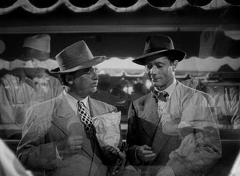 Movie still from “T-Men” (1947), directed by Anthony Mann – A black and white photo of two men in suits and hats; Medium shot, High angle