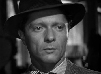 Movie still from “T-Men” (1947), directed by Anthony Mann – A black and white photo of a man wearing a hat; Close Up shot, Over the shoulder angle