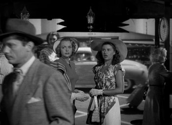 Movie still from “T-Men” (1947), directed by Anthony Mann – A couple of women standing next to each other on the street; Medium shot, Low angle