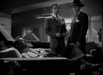 Movie still from “T-Men” (1947), directed by Anthony Mann – Three men standing in a room next to each other; Wide shot, High angle