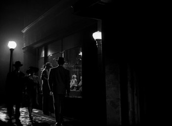 Movie still from “T-Men” (1947), directed by Anthony Mann – A group of people walking down a street at night; Wide shot, Low angle