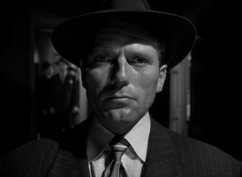 Movie still from “T-Men” (1947), directed by Anthony Mann – A black and white photo of a man wearing a suit and a hat; Close Up shot, Low angle