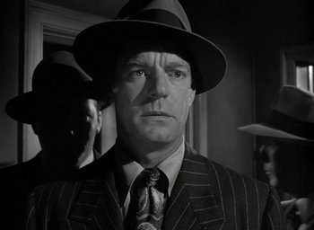 Movie still from “T-Men” (1947), directed by Anthony Mann – A man wearing a suit and a hat in black and white; Close Up shot, Low angle