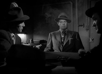 Movie still from “T-Men” (1947), directed by Anthony Mann – A black and white photo of a man in a suit and a hat; Medium shot, Over the shoulder angle