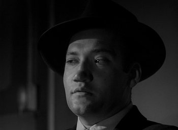 Movie still from “T-Men” (1947), directed by Anthony Mann – A black and white photo of a man wearing a hat; Close Up shot, Low angle