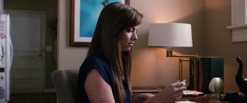 Movie still from “Table 19” (2017), directed by Jeffrey Blitz – A woman sitting in front of a lamp looking down at her phone; Close Up shot, High angle