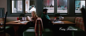 Movie still from “Table 19” (2017), directed by Jeffrey Blitz – A man and a woman sitting at a table in front of a laptop computer; Wide shot, High angle