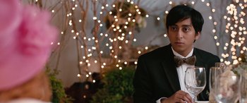 Movie still from “Table 19” (2017), directed by Jeffrey Blitz – A man in a suit standing in front of some lights; Close Up shot, Over the shoulder angle