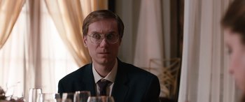 Movie still from “Table 19” (2017), directed by Jeffrey Blitz – A man in a suit and tie sitting at a table; Close Up shot, Over the shoulder angle