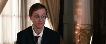 Movie still from “Table 19” (2017), directed by Jeffrey Blitz – A man in a suit and tie with a smirk on his face; Close Up shot, Over the shoulder angle