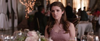 Movie still from “Table 19” (2017), directed by Jeffrey Blitz – A woman sitting at a table in front of flowers; Close Up shot, Over the shoulder angle