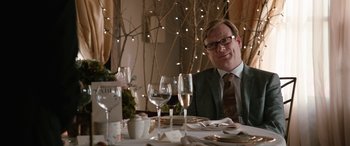 Movie still from “Table 19” (2017), directed by Jeffrey Blitz – A man sitting at a dinner table with wine glasses; Medium shot, Over the shoulder angle