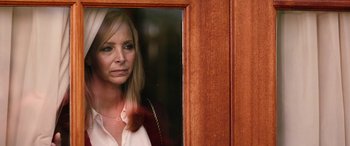 Movie still from “Table 19” (2017), directed by Jeffrey Blitz – A woman standing in front of a wooden door; Close Up shot, Over the shoulder angle