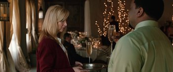Movie still from “Table 19” (2017), directed by Jeffrey Blitz – A woman holding a tray with a glass of champagne on top of it; Close Up shot, Over the shoulder angle