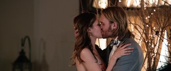Movie still from “Table 19” (2017), directed by Jeffrey Blitz – A man and a woman kissing each other in front of a wall; Close Up shot, Over the shoulder angle