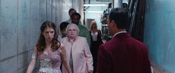 Movie still from “Table 19” (2017), directed by Jeffrey Blitz – A group of people in a hallway with a woman in a pink dress; Medium shot, Over the shoulder angle