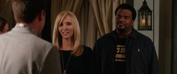 Movie still from “Table 19” (2017), directed by Jeffrey Blitz – A woman standing next to a man in front of a curtain; Close Up shot, Over the shoulder angle