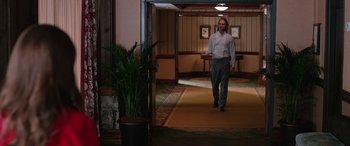 Movie still from “Table 19” (2017), directed by Jeffrey Blitz – A man in a suit and tie walking down a hall way; Wide shot, Low angle