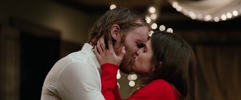 Movie still from “Table 19” (2017), directed by Jeffrey Blitz – A man and a woman kissing in front of lights; Close Up shot, Low angle