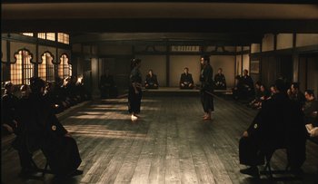 Movie still from “Taboo” (1999), directed by Nagisa Ôshima – Two people are practicing martial arts in an empty room; Wide shot, High angle