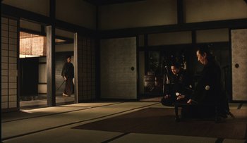 Movie still from “Taboo” (1999), directed by Nagisa Ôshima – A group of people sitting in a room; Wide shot, Over the shoulder angle