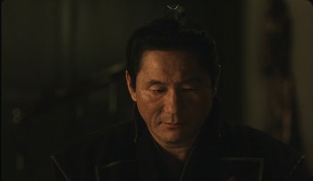 Movie still from “Taboo” (1999), directed by Nagisa Ôshima – A person wearing a black jacket; Close Up shot, Over the shoulder angle