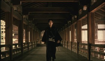 Movie still from “Taboo” (1999), directed by Nagisa Ôshima – A man in a black kimono holding a sword; Wide shot, Low angle