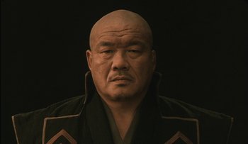 Movie still from “Taboo” (1999), directed by Nagisa Ôshima – An older bald man wearing a black jacket; Close Up shot, Low angle