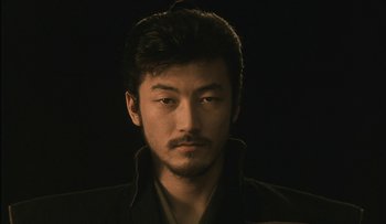 Movie still from “Taboo” (1999), directed by Nagisa Ôshima – A person wearing a jacket; Close Up shot, Low angle