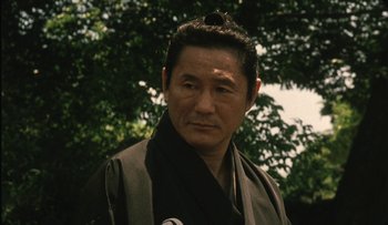 Movie still from “Taboo” (1999), directed by Nagisa Ôshima – A man in a black and brown kimono; Close Up shot, Low angle