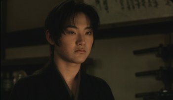 Movie still from “Taboo” (1999), directed by Nagisa Ôshima – A young asian man in a black kimono; Close Up shot, Low angle