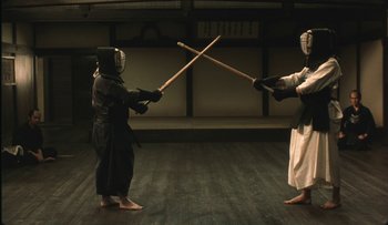 Movie still from “Taboo” (1999), directed by Nagisa Ôshima – Two people are practicing martial arts on a wooden floor; Wide shot, Low angle