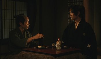 Movie still from “Taboo” (1999), directed by Nagisa Ôshima – Two men sitting at a table in front of each other; Medium shot, Over the shoulder angle