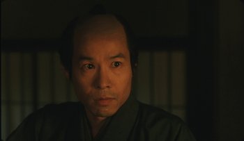 Movie still from “Taboo” (1999), directed by Nagisa Ôshima – A person wearing a green shirt; Close Up shot, Low angle