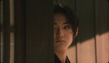 Movie still from “Taboo” (1999), directed by Nagisa Ôshima – A young man with short black hair looking at the camera; Close Up shot, Over the shoulder angle