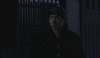 Movie still from “Taboo” (1999), directed by Nagisa Ôshima – A man in a black jacket is looking at the camera; Close Up shot, Over the shoulder angle