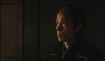 Movie still from “Taboo” (1999), directed by Nagisa Ôshima – A person in a dark room; Close Up shot, Low angle